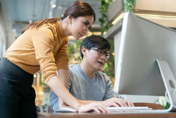Two person looking on a computer monitor