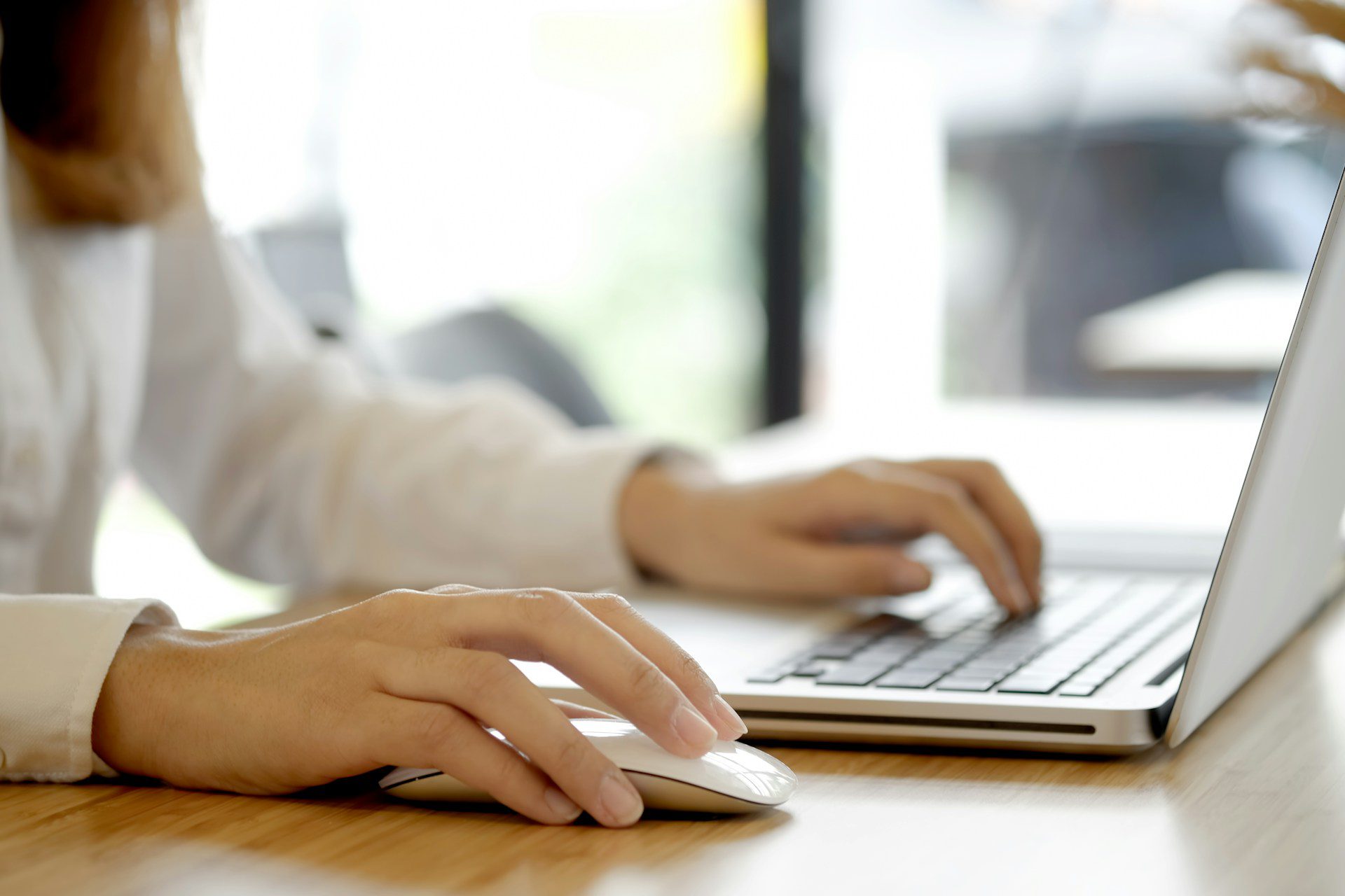 A person using a mouse and a laptop