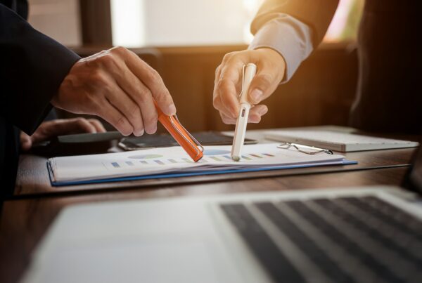 Two person pointing on a paper using a pen